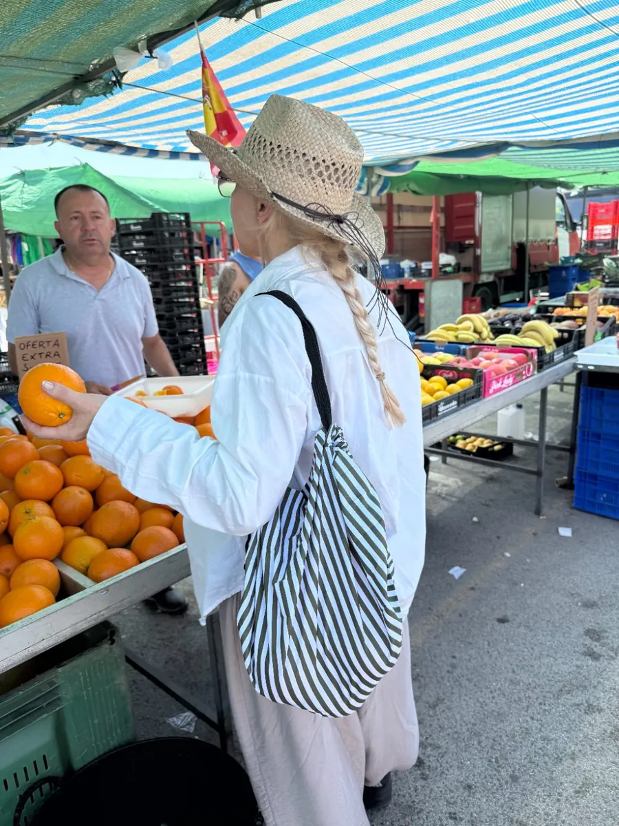 Person carrying a striped snaPockets tote at an outdoor market
